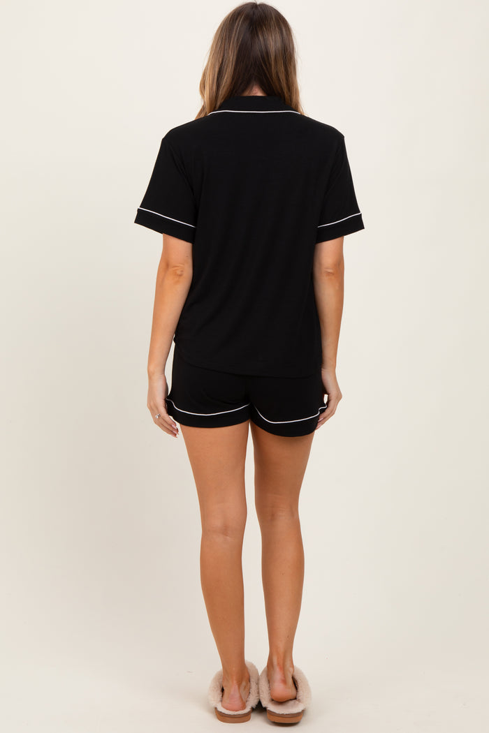 woman wearing a black short-sleeve pajama set with white piping details, shown from the back