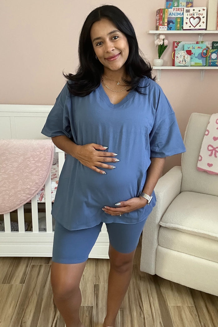 woman wearing a blue short sleeve maternity top and matching shorts with a visible baby bump
