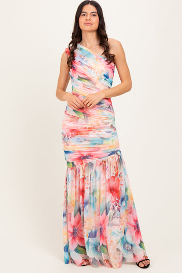 woman wearing a colorful one-shoulder floral maxi dress with ruching and a flowing skirt