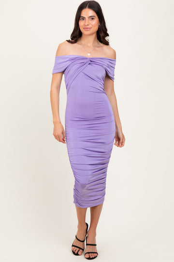 woman wearing a lavender off-the-shoulder ruched midi dress with a twist detail at the bust and a fitted silhouette