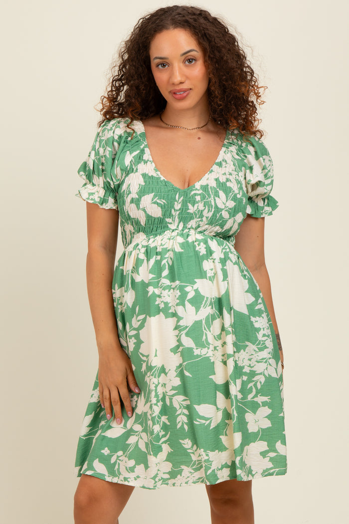woman wearing a green floral maternity dress with short puff sleeves and a smocked bodice