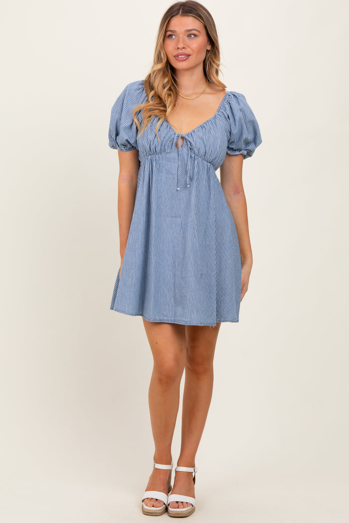 woman wearing a light blue striped puff sleeve dress with a tie front detail and a flared skirt