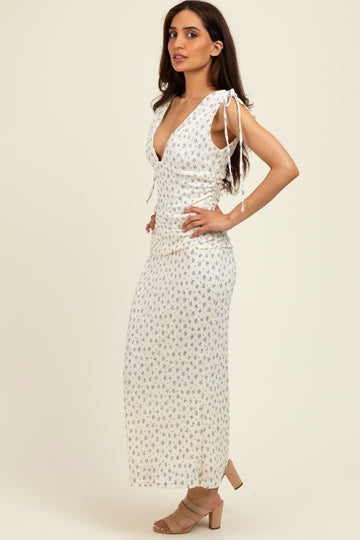 woman wearing a white floral maxi dress with tie straps and a deep v-neckline, standing sideways