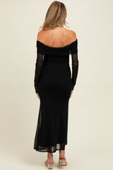 woman wearing a black off-the-shoulder maternity maxi dress with gathered detail and sheer long sleeves