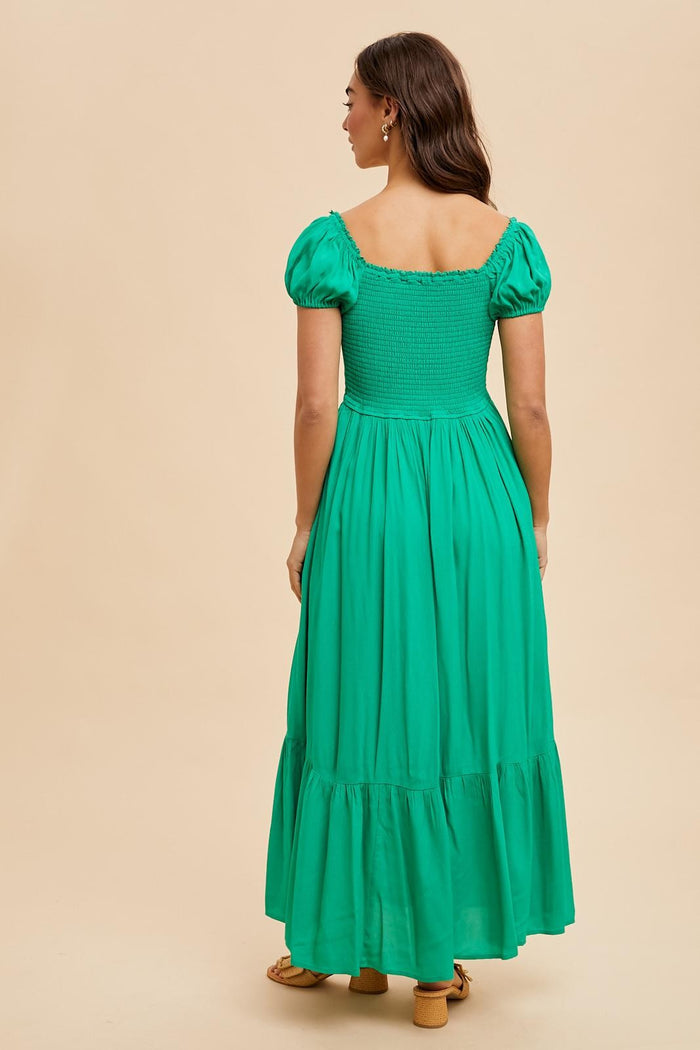woman wearing a green smocked back maxi dress with puff sleeves and a tiered skirt, shown from the back