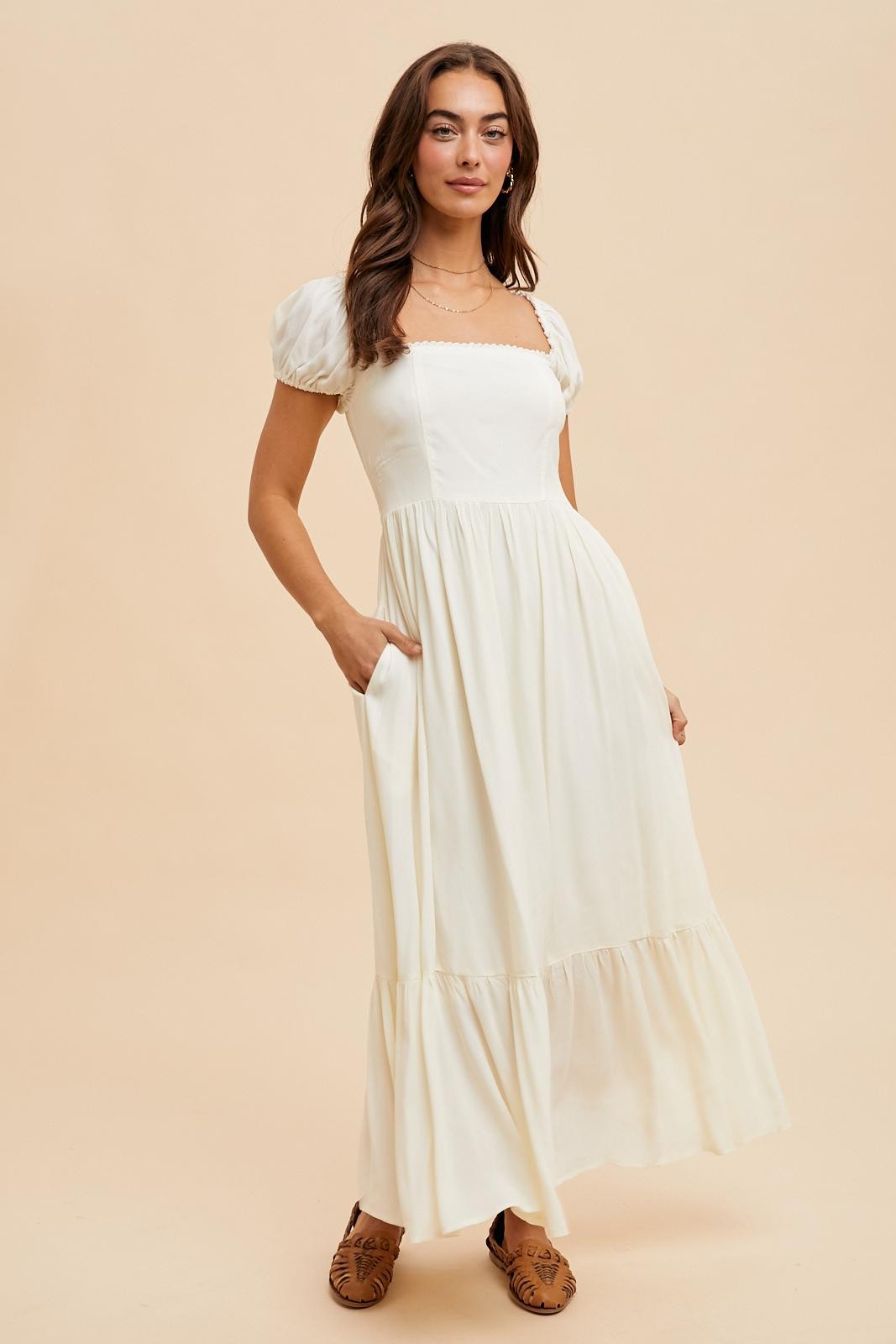 woman wearing a white puff sleeve maxi dress with a square neckline and pockets