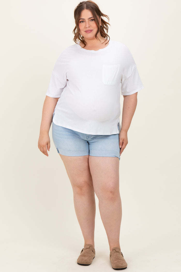 woman wearing a white short sleeve maternity top with a pocket and light blue denim shorts, showing her baby bump