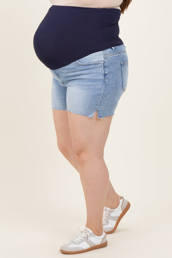 woman wearing light blue maternity plus denim shorts with a dark blue over-the-bump panel and a visible baby bump