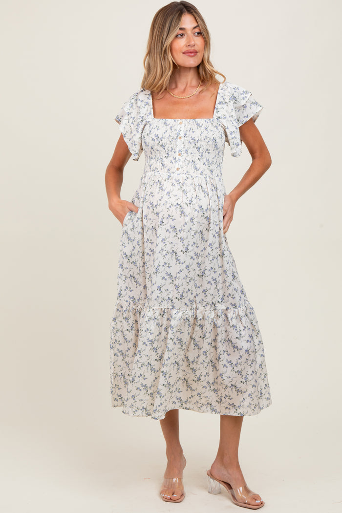 woman wearing a floral print maternity dress with ruffled sleeves and pockets, showcasing her baby bump