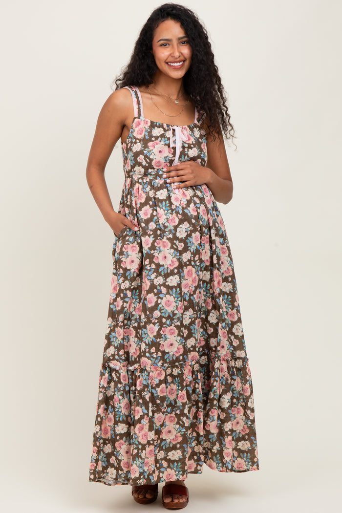 woman wearing a brown floral maternity maxi dress with adjustable straps and a baby bump.