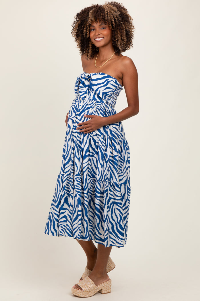 woman wearing a blue and white zebra print maternity dress with a fitted bodice and a flowing skirt, showing her baby bump