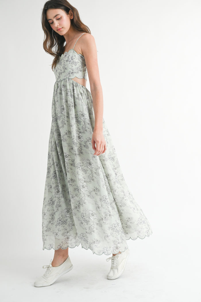 woman wearing a floral print maxi dress with cutout sides and scalloped hem, paired with white sneakers