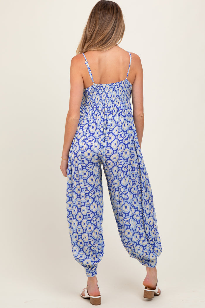 woman wearing a blue floral maternity jumpsuit with a smocked back and harem-style pant legs
