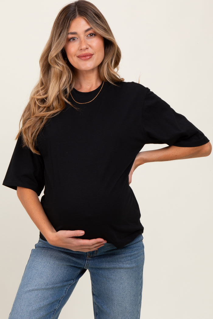 woman wearing a black maternity t-shirt and holding her baby bump, paired with blue jeans