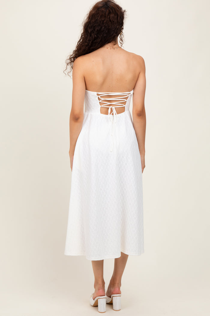 woman wearing a white strapless midi dress with a lace-up back and a flowy silhouette