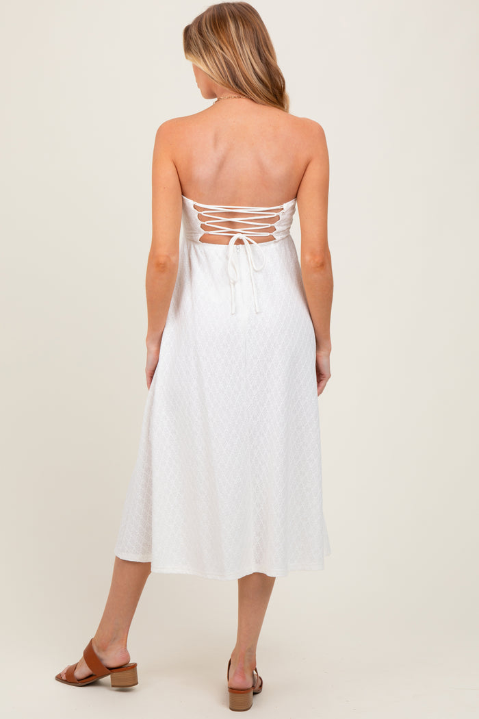 woman wearing a white strapless maternity dress with back lace-up details and a flowing midi length