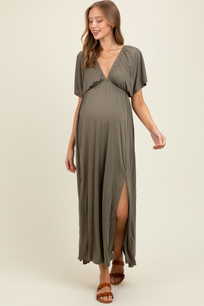 woman wearing an olive green short sleeve maternity maxi dress with a deep v-neck and a side slit, showing her baby bump