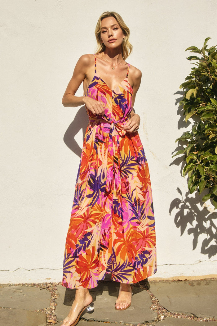 woman wearing a colorful floral maxi dress with spaghetti straps and a tied detail at the waist