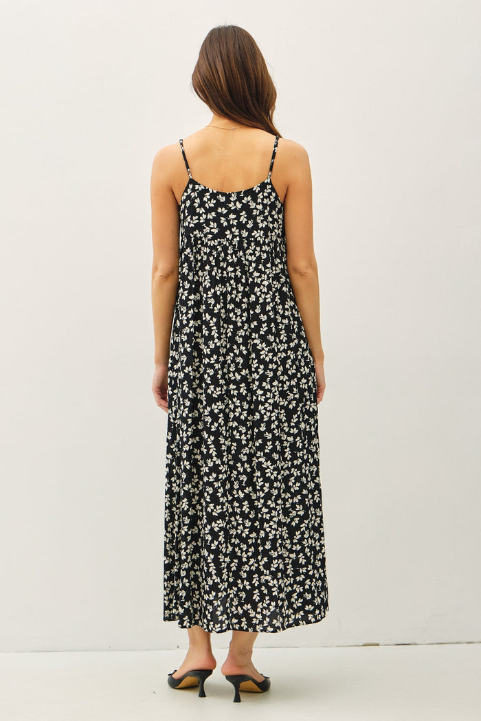 woman wearing a black floral maxi dress with spaghetti straps, seen from the back