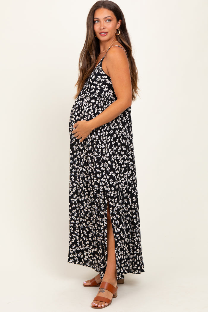 woman wearing a black and white floral maternity maxi dress with a side slit and holding her baby bump