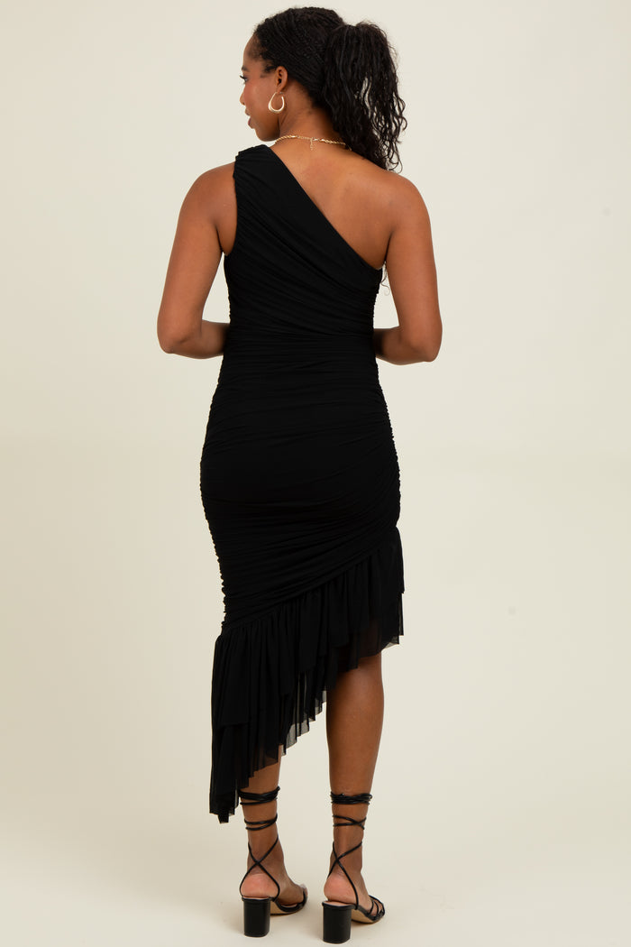 woman wearing a black one-shoulder ruched dress with a ruffled hem.