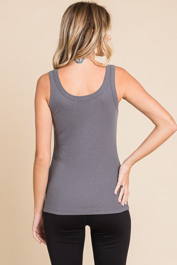 woman wearing a fitted gray ribbed tank top and black leggings, standing with her back to the camera
