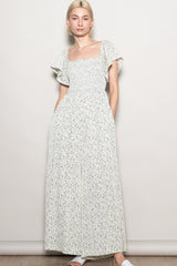 woman wearing a floral print maxi dress with short flutter sleeves and side pockets