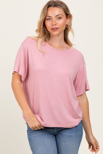 woman wearing a soft pink short sleeve top with a relaxed fit and round neckline, paired with light blue jeans