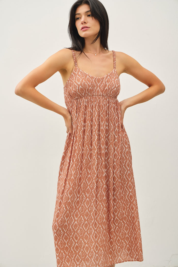 woman wearing a brown patterned maxi dress with spaghetti straps and a fitted bodice