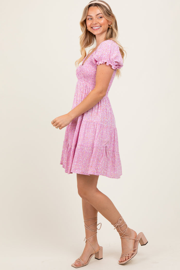 woman wearing a pink floral puff sleeve mini dress and beige strappy sandals, smiling and posing sideways