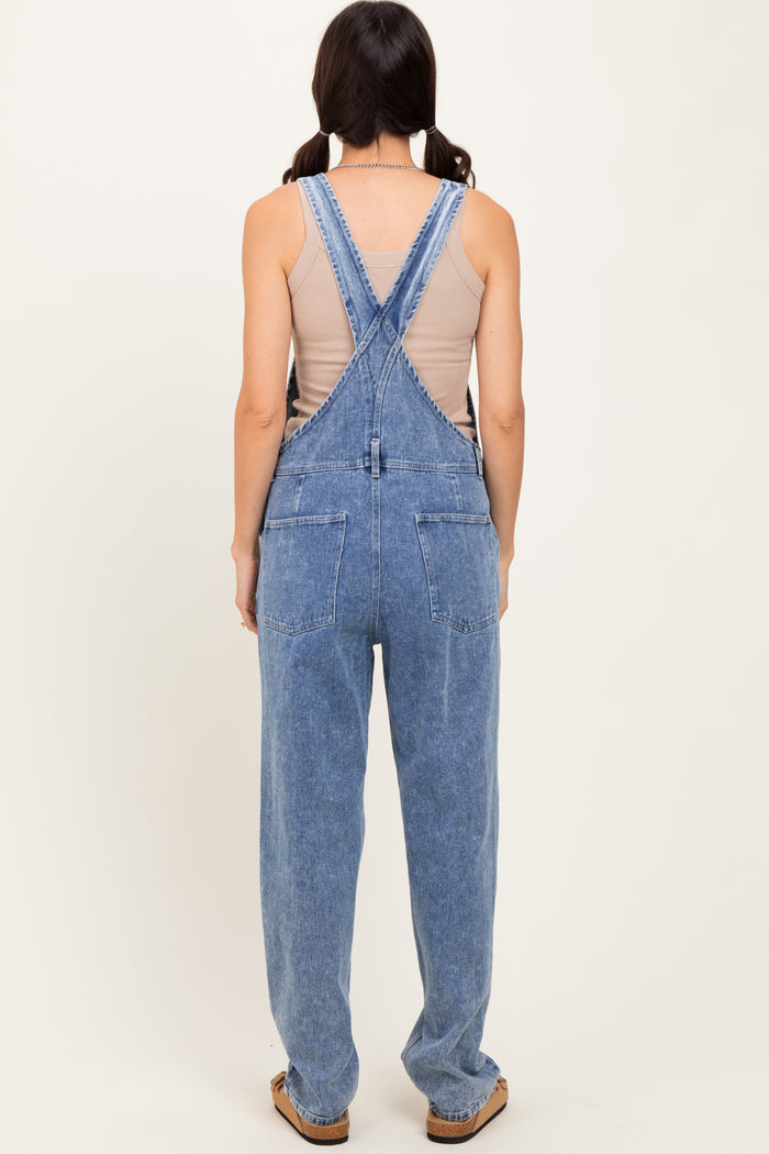 woman wearing a back view of light blue denim overalls with a relaxed fit and adjustable straps