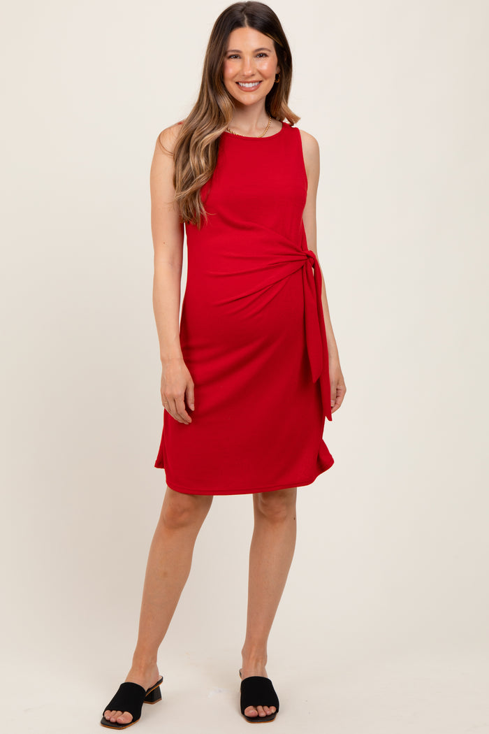 woman wearing a red maternity dress with a side tie detail and a flattering silhouette, styled with black sandals