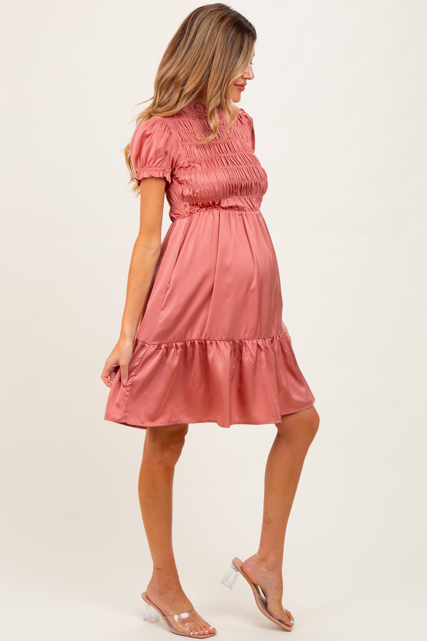 woman wearing a dusty rose maternity dress with smocked bodice and tiered skirt, showcasing her baby bump
