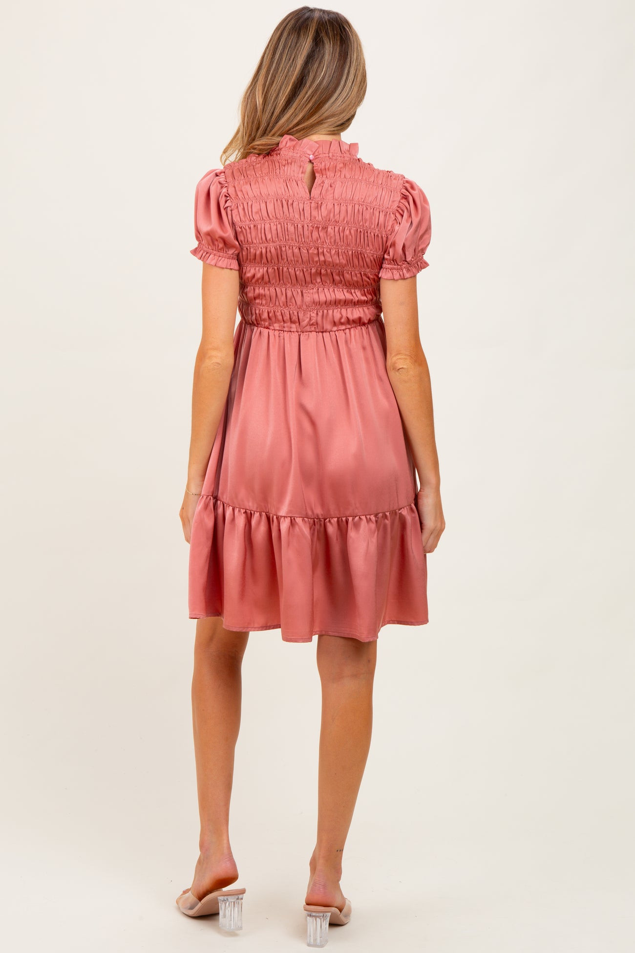 woman wearing a rose pink maternity dress with smocked bodice and ruffled hem, viewed from the back