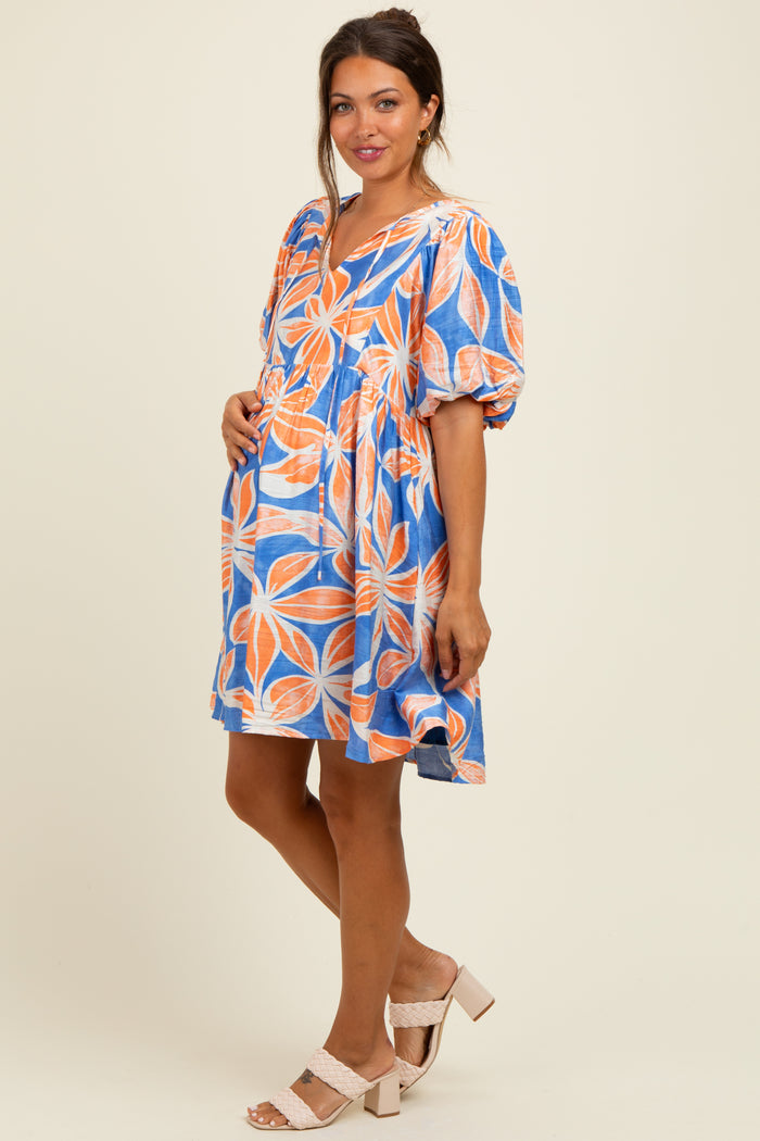 woman wearing a colorful floral print maternity dress with puff sleeves and a visible baby bump