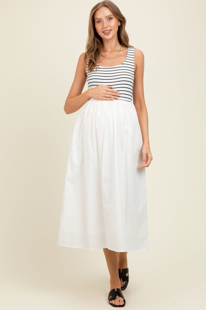 woman wearing a black and white striped maternity dress with a flowy white skirt, holding her baby bump