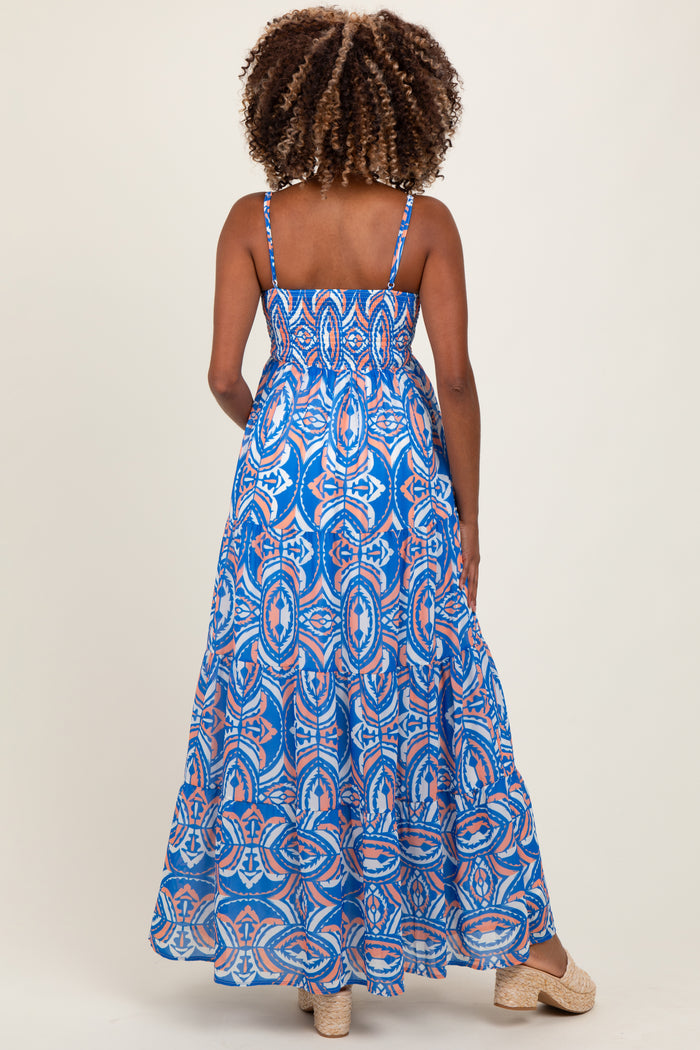 woman wearing a blue patterned maternity maxi dress with thin straps, showing a baby bump from the back