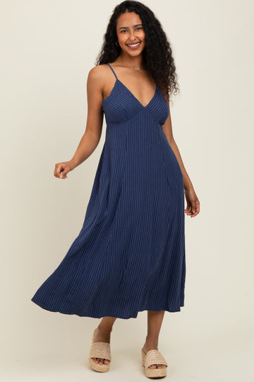 woman wearing a navy blue striped maxi dress with spaghetti straps and a flowing skirt
