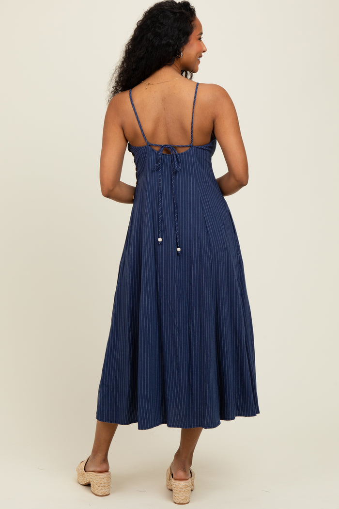 woman wearing a navy striped midi dress with adjustable spaghetti straps and an open back detail