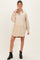 woman wearing a beige corduroy maternity shirt dress with buttons and long sleeves, smiling and standing confidently
