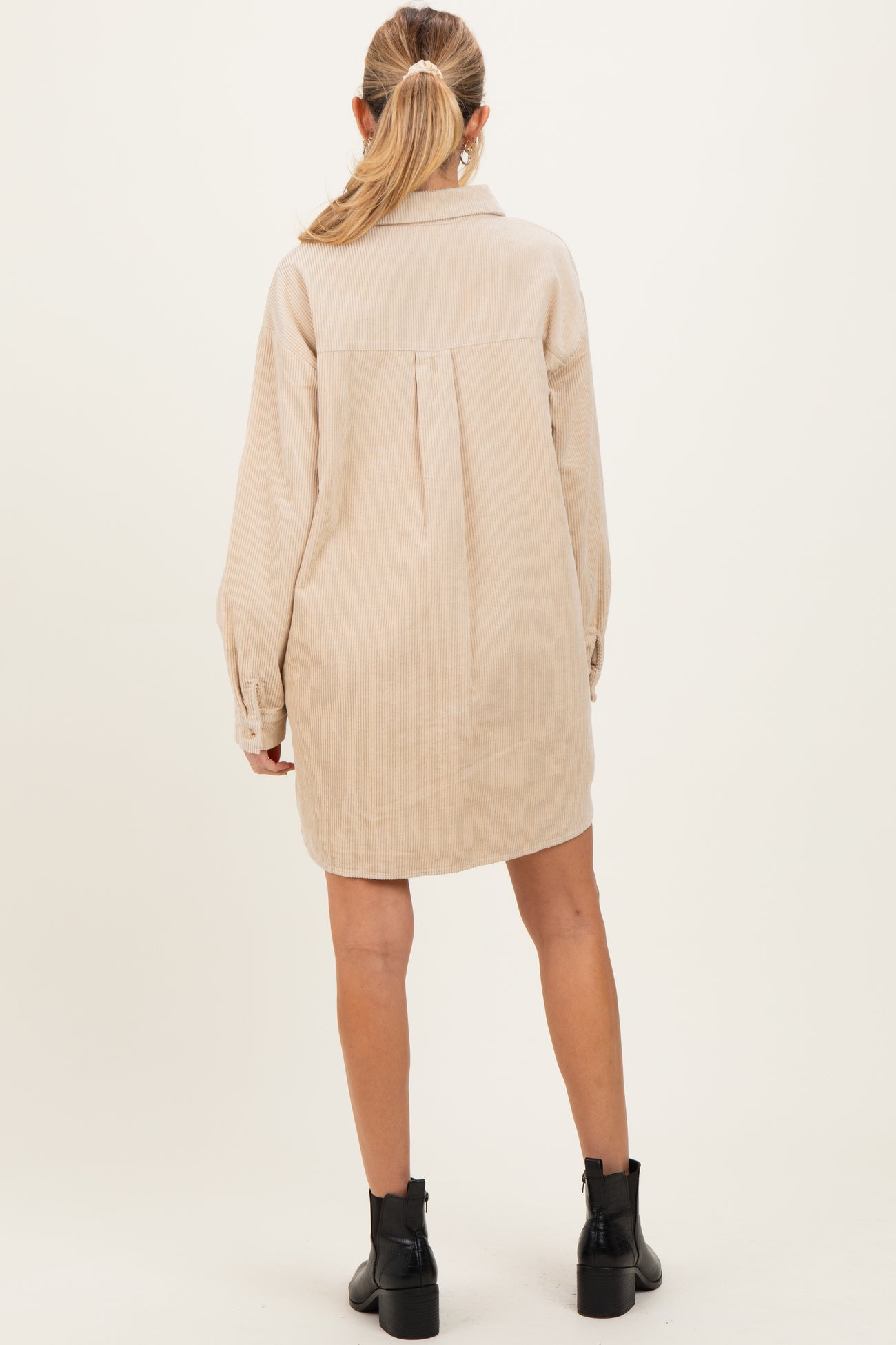 woman wearing a beige corduroy maternity shirt dress with a relaxed fit and back pleat detail