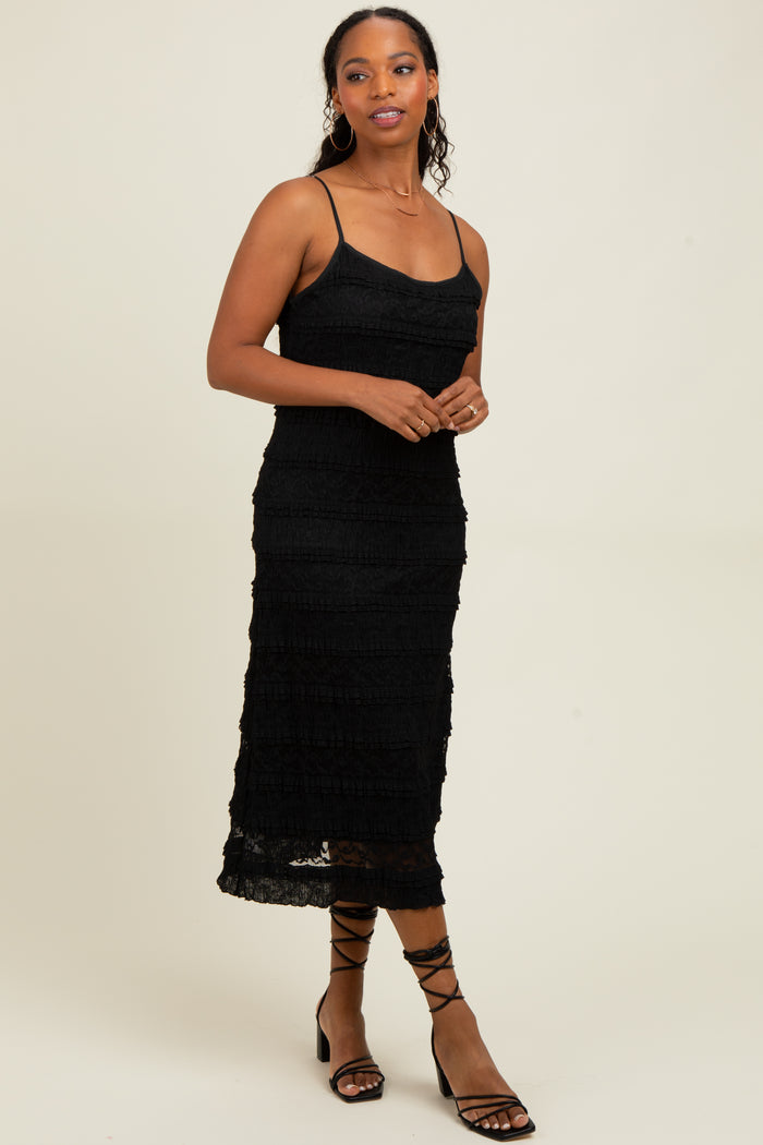 woman wearing a black spaghetti strap midi dress with a tiered ruffle design and styled with strappy black sandals