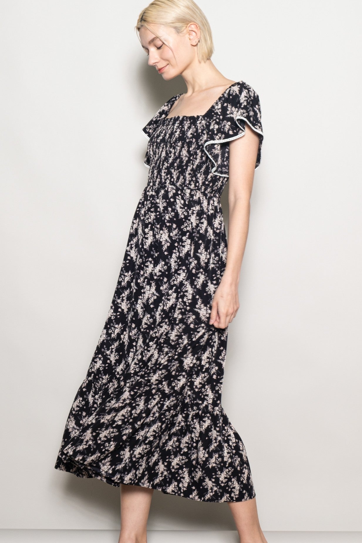 woman wearing a black floral midi dress with ruffled sleeves and a smocked bodice