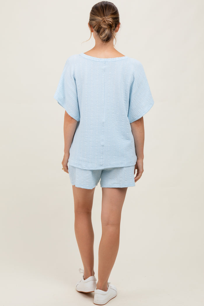 woman wearing a light blue maternity short set with a loose fit and short sleeves from the back