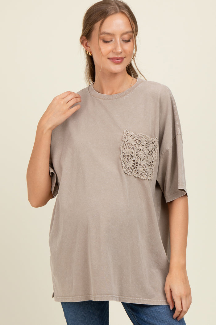 woman wearing a taupe maternity top with a lace pocket detail and a visible baby bump