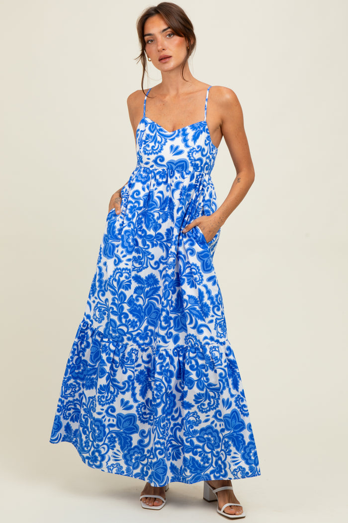 woman wearing a blue and white floral maxi dress with spaghetti straps and pockets