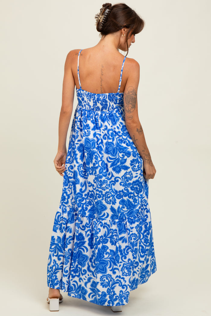 woman wearing a blue and white floral print maxi dress with thin straps and a tiered skirt, viewed from the back