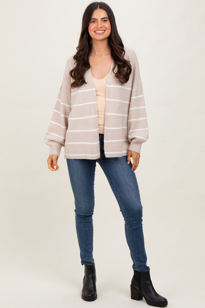 woman wearing a beige striped cardigan over a light top and blue skinny jeans, paired with black ankle boots