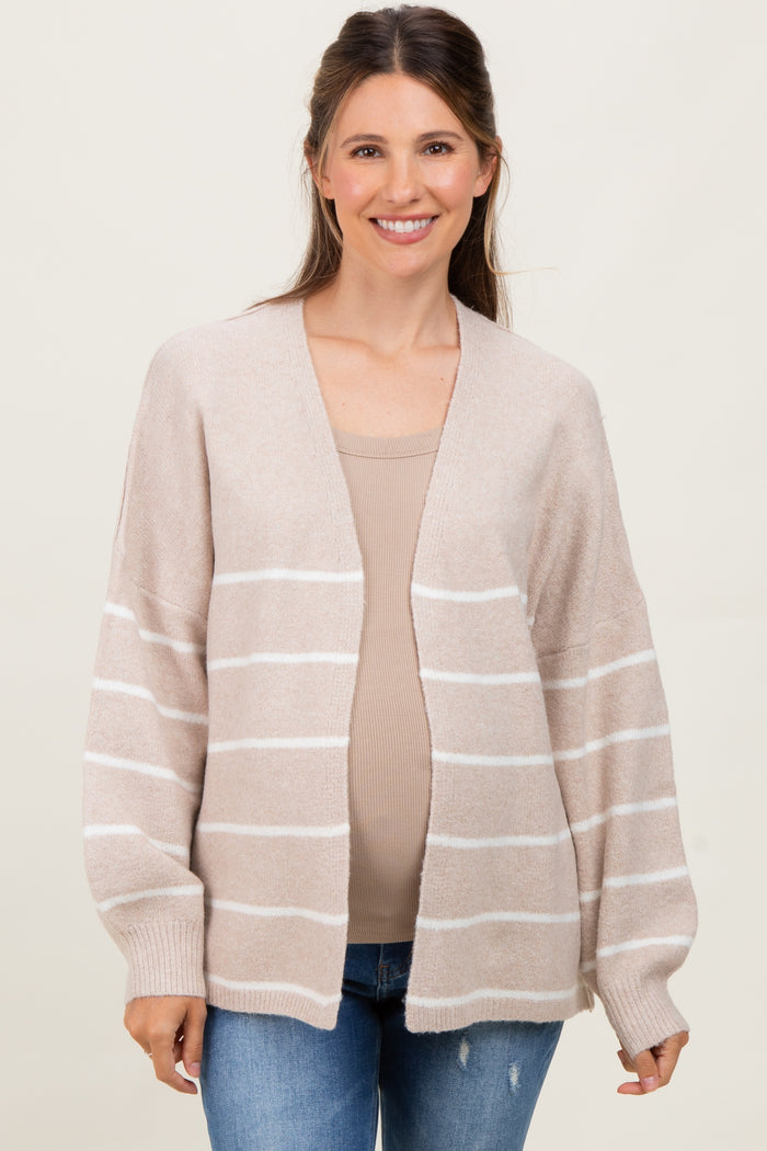 woman wearing a beige and white striped maternity cardigan over a fitted top and showing her baby bump