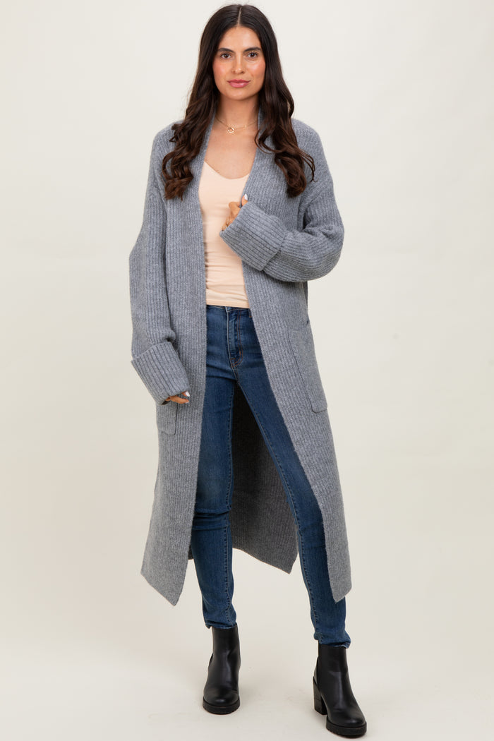 woman wearing a long grey ribbed cardigan over a beige top and blue jeans, paired with black ankle boots